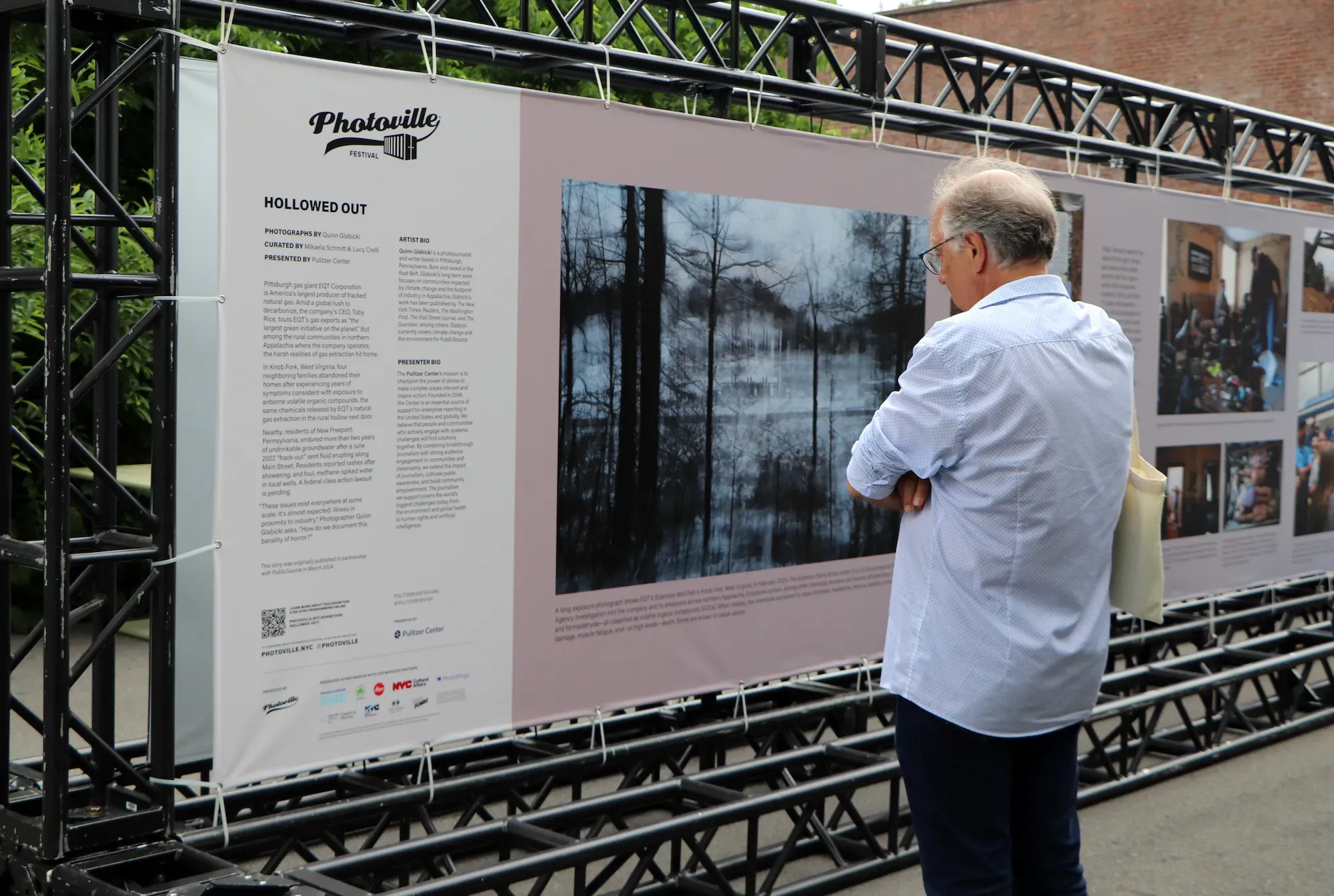 Man in blue shirt reads text on Photoville banner.
